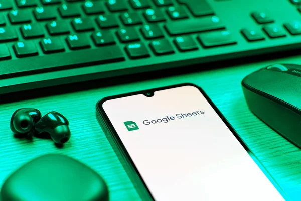Prag, Çek Cumhuriyeti - 08 12 2025: Google Sheets logosunu gösteren klavyesi ve cep telefonu olan bir masanın yan görüntüsü. Google Sayfalar tablo oluşturmak ve yönetmek için bir platformdur.