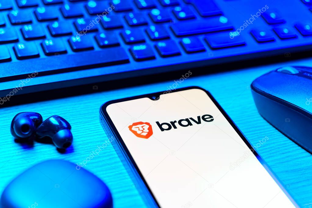 Prague, Czechia - 08 12 2025: A side view of a desk with a keyboard and a mobile phone displaying the Brave logo. Brave is a web browser focused on privacy and speed.