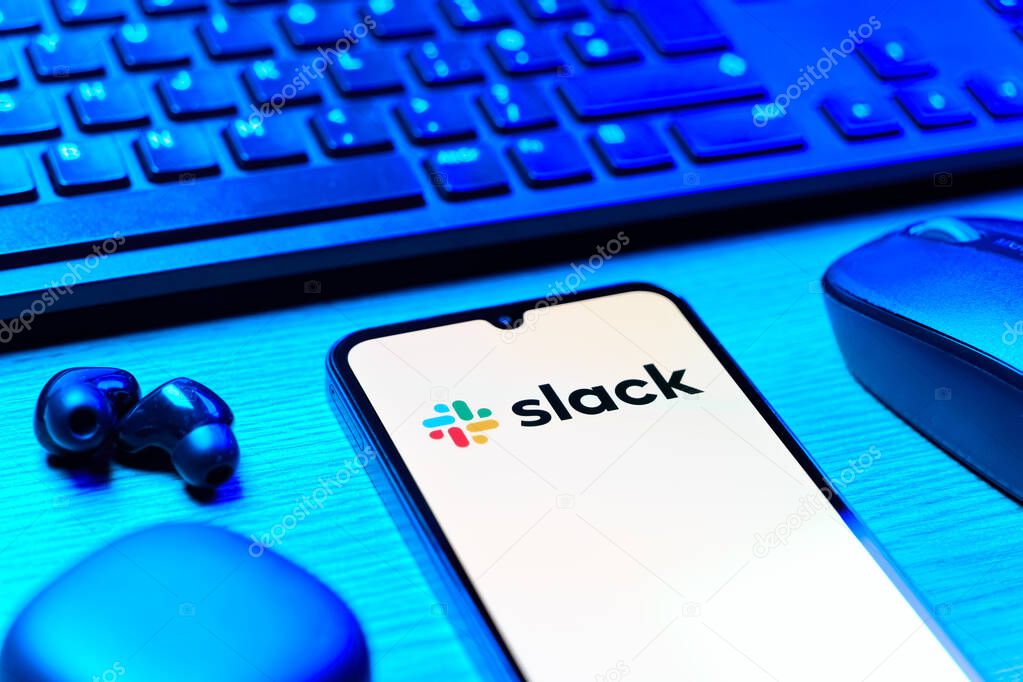Prague, Czechia - 08 12 2025: A side view of a desk with a keyboard and a mobile phone displaying the Slack logo. Slack is a platform for team messaging and workplace communication.