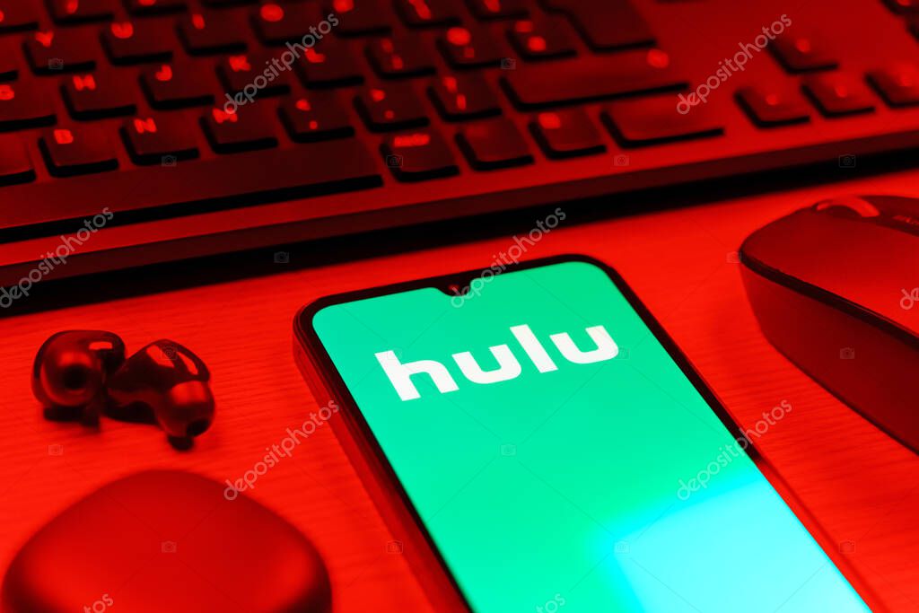 Prague, Czechia - 08 12 2025: A side view of a desk with a keyboard and a mobile phone displaying the Hulu logo. Hulu is a streaming platform for TV shows, movies, and live TV.