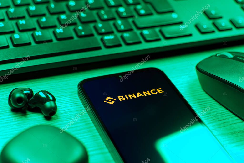 Prague, Czechia - 08 12 2025: A side view of a desk with a keyboard and a mobile phone displaying the Binance logo. Binance is a cryptocurrency exchange for trading digital assets.