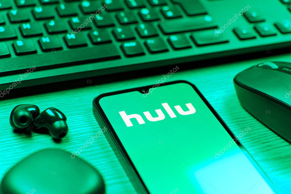 Prague, Czechia - 08 12 2025: A side view of a desk with a keyboard and a mobile phone displaying the Hulu logo. Hulu is a streaming platform for TV shows, movies, and live TV.