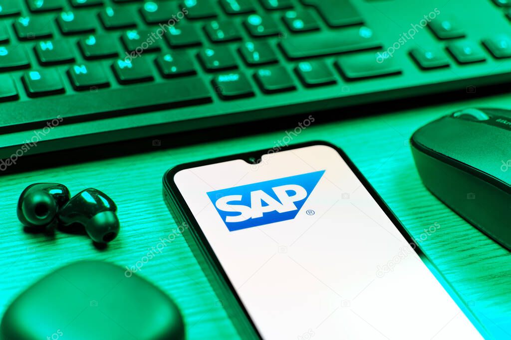 Prague, Czechia - 08 12 2025: A side view of a desk with a keyboard and a mobile phone displaying the SAP logo. SAP is a software company providing enterprise applications and solutions.