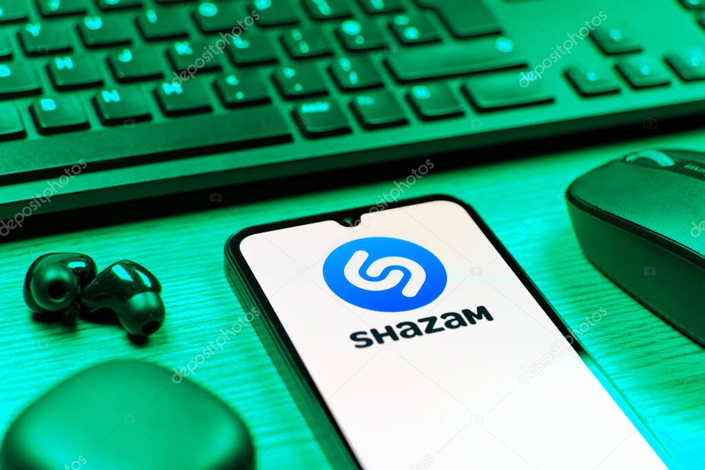 Prague, Czechia - 08 12 2025: A side view of a desk with a keyboard and a mobile phone displaying the Shazam logo. Shazam is an app for identifying songs and music tracks.