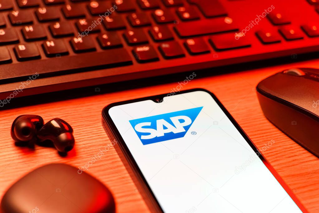 Prague, Czechia - 08 12 2025: A side view of a desk with a keyboard and a mobile phone displaying the SAP logo. SAP is a software company providing enterprise applications and solutions.