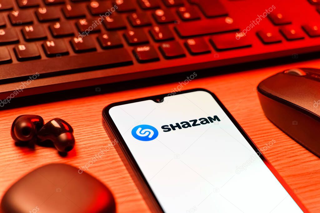 Prague, Czechia - 08 12 2025: A side view of a desk with a keyboard and a mobile phone displaying the Shazam logo. Shazam is an app for identifying songs and music tracks.