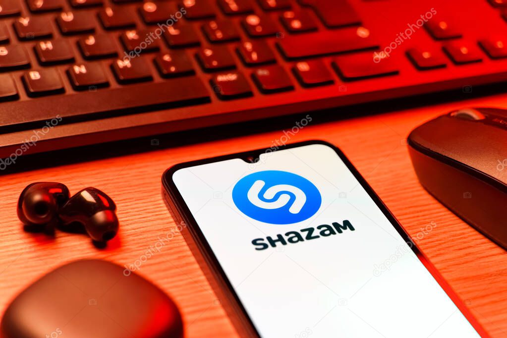 Prague, Czechia - 08 12 2025: A side view of a desk with a keyboard and a mobile phone displaying the Shazam logo. Shazam is an app for identifying songs and music tracks.