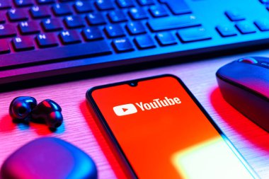 Prague, Czechia - 08 12 2025: A side view of a desk with a keyboard and a mobile phone displaying the Youtube logo. Youtube is a platform to watch and share videos worldwide.