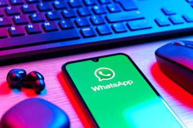 Prague, Czechia - 08 12 2025: A side view of a desk with a keyboard and a mobile phone displaying the WhatsApp logo. WhatsApp is an app for sending texts, calls, and media.