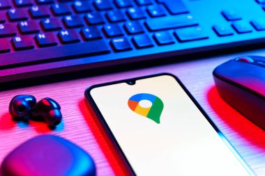 Prague, Czechia - 08 12 2025: A side view of a desk with a keyboard and a mobile phone displaying the Google Maps logo. Google Maps is a platform for maps, navigation, and location services.