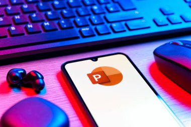 Prague, Czechia - 08 12 2025: A side view of a desk with a keyboard and a mobile phone displaying the Powerpoint logo. Powerpoint is a software for creating presentations and slideshows.