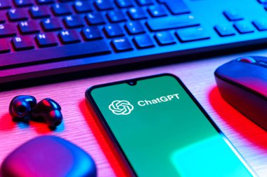 Prague, Czechia - 08 12 2025: A side view of a desk with a keyboard and a mobile phone displaying the ChatGPT logo. ChatGPT is an AI chatbot for generating text and answering questions.