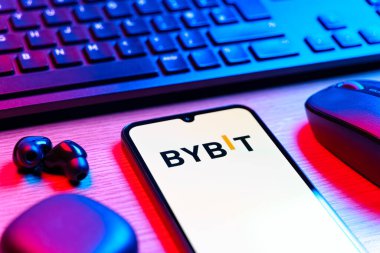 Prague, Czechia - 08 12 2025: A side view of a desk with a keyboard and a mobile phone displaying the Bybit logo. Bybit is a platform for trading cryptocurrencies and derivatives.