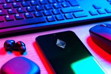 Prague, Czechia - 08 12 2025: A side view of a desk with a keyboard and a mobile phone displaying the Ethereum logo. Ethereum is a blockchain platform for decentralized applications and crypto.