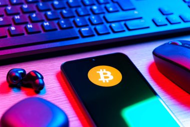 Prag, Çek Cumhuriyeti - 08 12 2025: Bitcoin logosunu gösteren klavyesi ve cep telefonu olan bir masanın yan görüntüsü. Bitcoin merkezi olmayan işlemler için dijital bir kripto para birimidir.