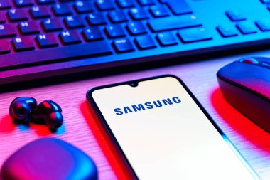 Prag, Çek Cumhuriyeti - 08 12 2025: Samsung logosunu gösteren klavyesi ve cep telefonu olan bir masanın yan görüntüsü. Samsung elektronik ve cihaz üreten bir teknoloji şirketi..