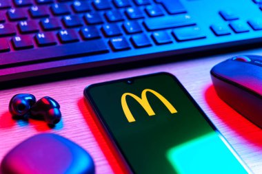 Prag, Çek Cumhuriyeti - 08 12 2025: McDonalds logosunu gösteren klavyesi ve cep telefonu olan bir masanın yan görüntüsü. McDonalds hamburger, patates kızartması ve daha fazlası sunan bir fast-food zinciri..