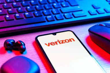 Prag, Çek Cumhuriyeti - 08 12 2025: Verizon logosunu gösteren klavyeli ve cep telefonlu bir masanın yan görüntüsü. Verizon, kablosuz ve geniş bant hizmetleri sağlayan bir telekom şirketidir..