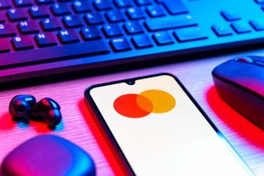 Prag, Çek Cumhuriyeti - 08 12 2025: Mastercard logosunu gösteren klavyesi ve cep telefonu olan bir masanın yan görüntüsü. Mastercard ödeme kartları ve hizmetler sağlayan bir finans şirketidir..
