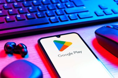 Prag, Çek Cumhuriyeti - 08 12 2025: Google Play logosunu gösteren klavyesi ve cep telefonu olan bir masanın yan görüntüsü. Google Play uygulamaları, oyunları ve dijital içeriği indirmek için bir platformdur.