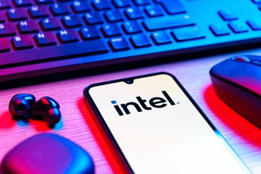 Prag, Çek Cumhuriyeti - 08 12 2025: Intel logosunu gösteren klavyesi ve cep telefonu olan bir masanın yan görüntüsü. Intel işlemci ve bilgisayar donanımı üreten bir teknoloji şirketidir..