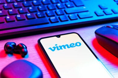 Prag, Çek Cumhuriyeti - 08 12 2025: Vimeo logosunu gösteren klavyesi ve cep telefonu olan bir masanın yan görüntüsü. Vimeo, yüksek kaliteli video sunucu ve paylaşımı için bir platformdur.