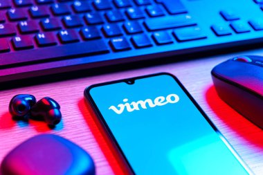 Prag, Çek Cumhuriyeti - 08 12 2025: Vimeo logosunu gösteren klavyesi ve cep telefonu olan bir masanın yan görüntüsü. Vimeo, yüksek kaliteli video sunucu ve paylaşımı için bir platformdur.