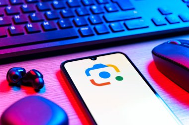 Prag, Çek Cumhuriyeti - 08 12 2025: Google Lens logosunu gösteren klavyesi ve cep telefonu olan bir masanın yan görüntüsü. Google Lens, resimlerdeki görsel arama ve bilgi için kullanılan bir araçtır..