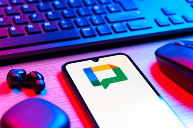 Prag, Çek Cumhuriyeti - 08 12 2025: Google Chat logosunu gösteren klavyesi ve cep telefonu olan bir masanın yan görüntüsü. Google Chat mesajlaşma ve takım işbirliği için bir platformdur.