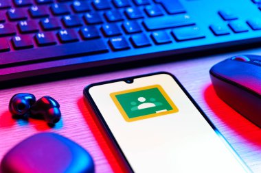Prag, Çek Cumhuriyeti - 08 12 2025: Google Sınıfı logosunu gösteren klavyesi ve cep telefonu olan bir masanın yan görüntüsü. Google Sınıfı, sınıfları ve eğitim içeriğini yönetmek için bir platformdur.