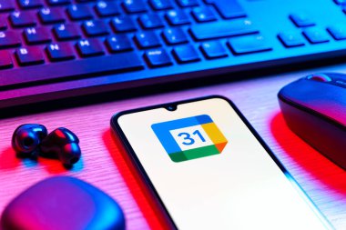 Prag, Çek Cumhuriyeti - 08 12 2025: Google Takvim logosunu gösteren klavyesi ve cep telefonu olan bir masanın yan görüntüsü. Google Takvimi olayları zamanlamak ve yönetmek için bir platformdur.