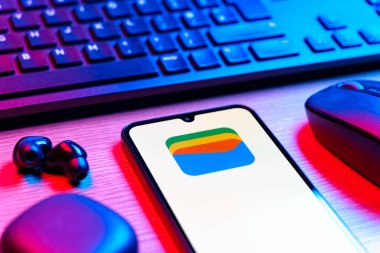 Prag, Çek Cumhuriyeti - 08 12 2025: Google Cüzdan logosunu gösteren klavyesi ve cep telefonu olan bir masanın yan görüntüsü. Google Cüzdanı dijital ödeme yöntemlerini depolamak ve kullanmak için bir platformdur.