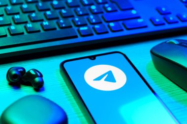 Prague, Czechia - 08 12 2025: A side view of a desk with a keyboard and a mobile phone displaying the Telegram logo. Telegram is an app for fast and secure messaging.
