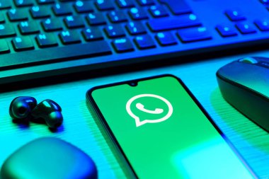 Prague, Czechia - 08 12 2025: A side view of a desk with a keyboard and a mobile phone displaying the WhatsApp logo. WhatsApp is an app for sending texts, calls, and media.