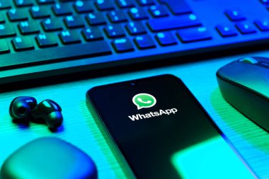 Prague, Czechia - 08 12 2025: A side view of a desk with a keyboard and a mobile phone displaying the WhatsApp logo. WhatsApp is an app for sending texts, calls, and media.