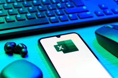 Prague, Czechia - 08 12 2025: A side view of a desk with a keyboard and a mobile phone displaying the Excel logo. Excel is a software for spreadsheets, data analysis, and calculations.
