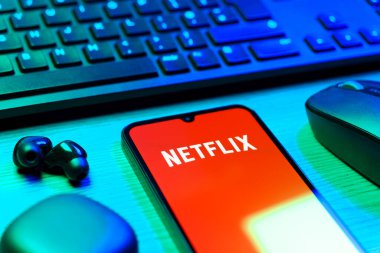 Prague, Czechia - 08 12 2025: A side view of a desk with a keyboard and a mobile phone displaying the Netflix logo. Netflix is a streaming platform for movies and TV shows.