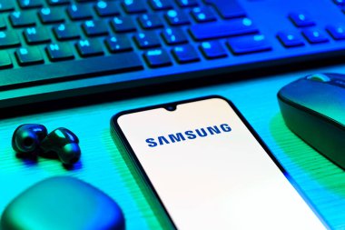 Prag, Çek Cumhuriyeti - 08 12 2025: Samsung logosunu gösteren klavyesi ve cep telefonu olan bir masanın yan görüntüsü. Samsung elektronik ve cihaz üreten bir teknoloji şirketi..