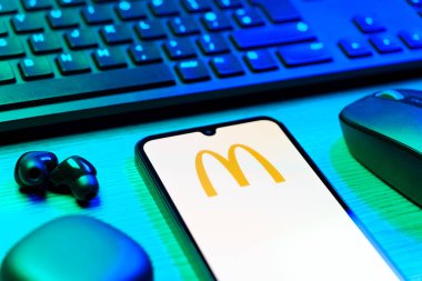 Prag, Çek Cumhuriyeti - 08 12 2025: McDonalds logosunu gösteren klavyesi ve cep telefonu olan bir masanın yan görüntüsü. McDonalds hamburger, patates kızartması ve daha fazlası sunan bir fast-food zinciri..