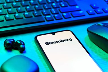 Prag, Çek Cumhuriyeti - 08 12 2025: Bloomberg logosunu gösteren klavyesi ve cep telefonu olan bir masanın yan görüntüsü. Bloomberg finansal haberler, veriler ve analizler sağlayan bir şirkettir..