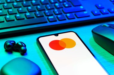 Prag, Çek Cumhuriyeti - 08 12 2025: Mastercard logosunu gösteren klavyesi ve cep telefonu olan bir masanın yan görüntüsü. Mastercard ödeme kartları ve hizmetler sağlayan bir finans şirketidir..