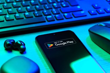 Prag, Çek Cumhuriyeti - 08 12 2025: Google Play logosunu gösteren klavyesi ve cep telefonu olan bir masanın yan görüntüsü. Google Play uygulamaları, oyunları ve dijital içeriği indirmek için bir platformdur.