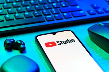 Prag, Çek Cumhuriyeti - 08 12 2025: Youtube Stüdyo logosunu gösteren klavyesi ve cep telefonu olan bir masanın yan görüntüsü. Youtube Studio YouTube kanallarını yönetmek ve analiz etmek için bir platformdur.