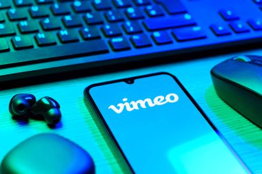 Prag, Çek Cumhuriyeti - 08 12 2025: Vimeo logosunu gösteren klavyesi ve cep telefonu olan bir masanın yan görüntüsü. Vimeo, yüksek kaliteli video sunucu ve paylaşımı için bir platformdur.
