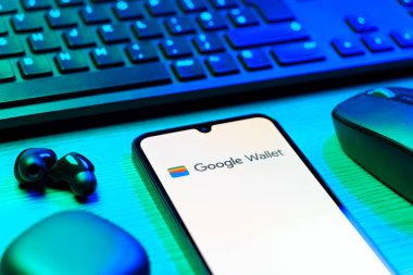Prag, Çek Cumhuriyeti - 08 12 2025: Google Cüzdan logosunu gösteren klavyesi ve cep telefonu olan bir masanın yan görüntüsü. Google Cüzdanı dijital ödeme yöntemlerini depolamak ve kullanmak için bir platformdur.