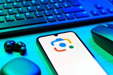 Prag, Çek Cumhuriyeti - 08 12 2025: Google Lens logosunu gösteren klavyesi ve cep telefonu olan bir masanın yan görüntüsü. Google Lens, resimlerdeki görsel arama ve bilgi için kullanılan bir araçtır..