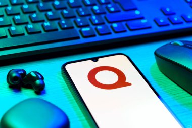 Prag, Çek Cumhuriyeti - 08 12 2025: Quora logosunu gösteren klavyesi ve cep telefonu olan bir masanın yan görüntüsü. Quora soru sormak ve bilgi paylaşmak için bir platformdur..