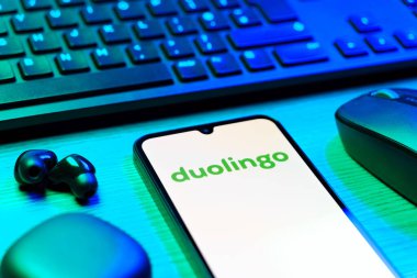 Prag, Çek Cumhuriyeti - 08 12 2025: Duolingo logosunu gösteren klavyesi ve cep telefonu olan bir masanın yan görüntüsü. Duolingo interaktif olarak dil öğrenmek için bir platformdur..