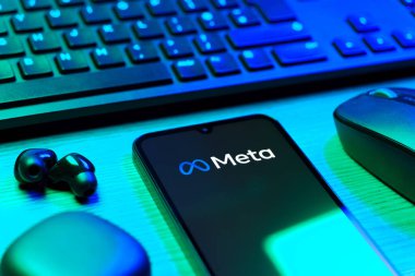 Prague, Czechia - 08 12 2025: A side view of a desk with a keyboard and a mobile phone displaying the Meta logo. Meta is a company offering social platforms like Facebook and Instagram.
