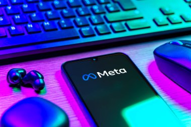 Prague, Czechia - 08 12 2025: A side view of a desk with a keyboard and a mobile phone displaying the Meta logo. Meta is a company offering social platforms like Facebook and Instagram.